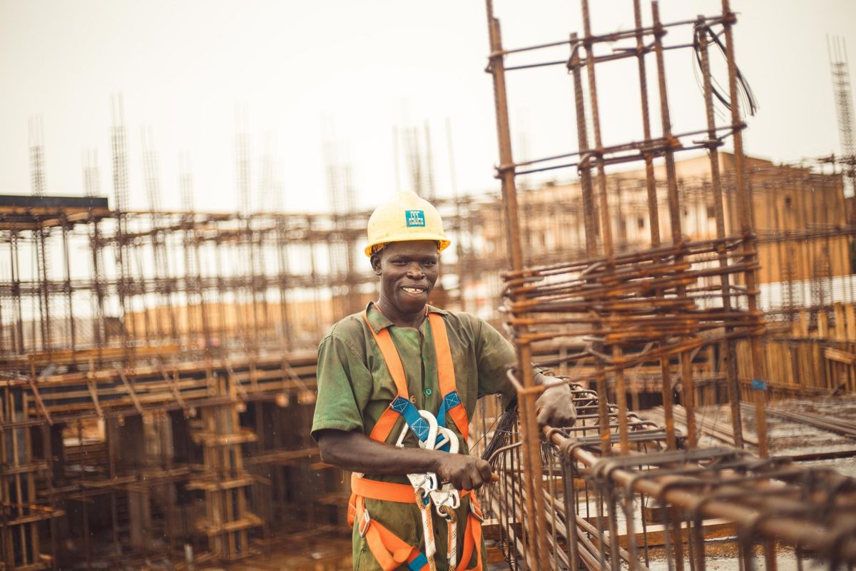 A smiling construction worker in a hard hat on a building site
